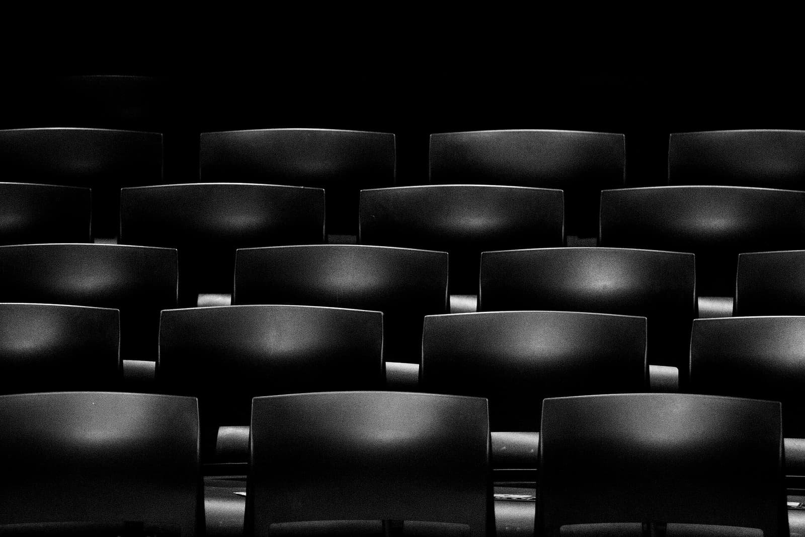 Filas de butacas de cine vacías, en blanco y negro
